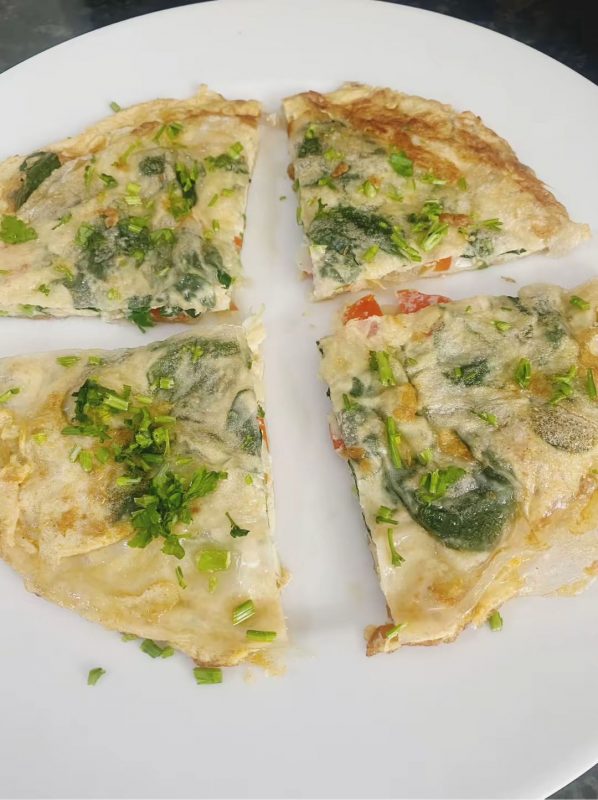 Rice paper omelette sliced into quarters and garnished with fresh herbs on a plate