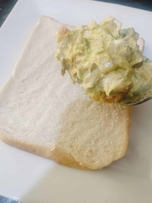 Spreading creamy mackerel rillettes mixture onto sliced bread to make a sandwich