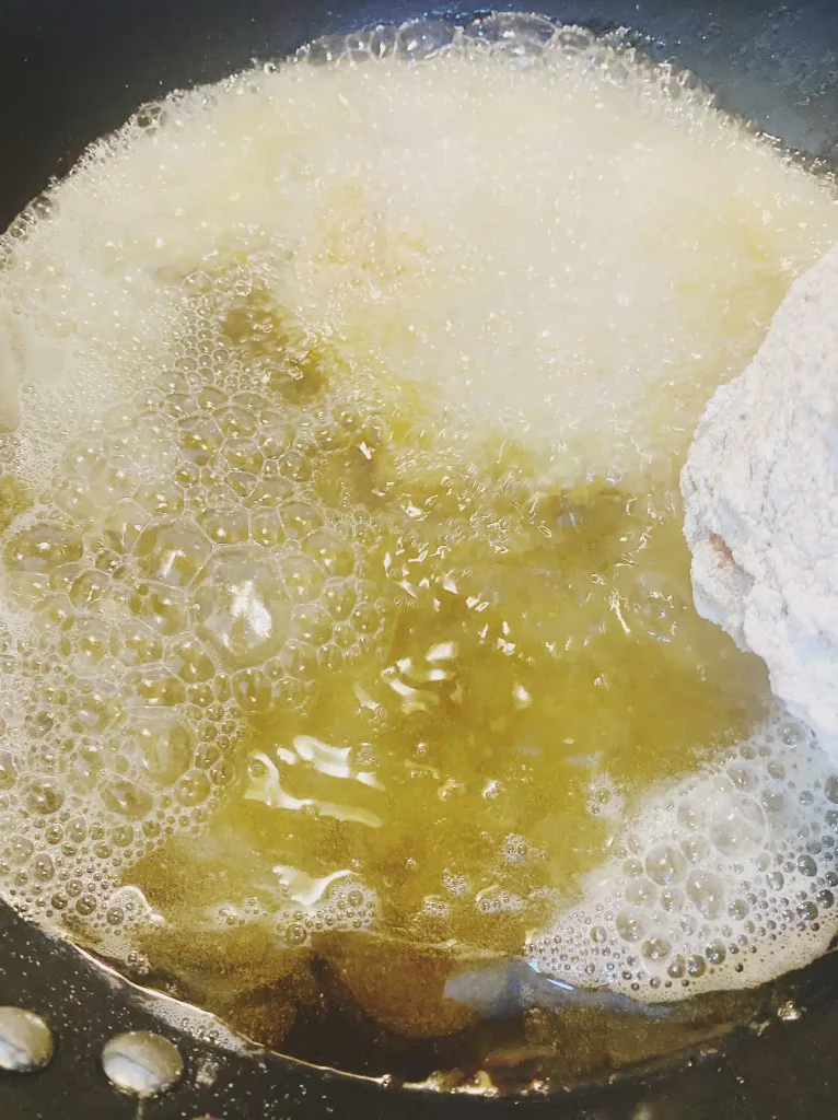 Chicken thighs frying in hot oil for crispy texture.