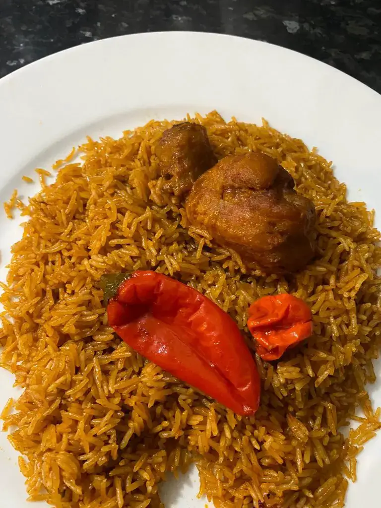 A vibrant plate of Jollof rice, garnished with fresh herbs and served with sides.