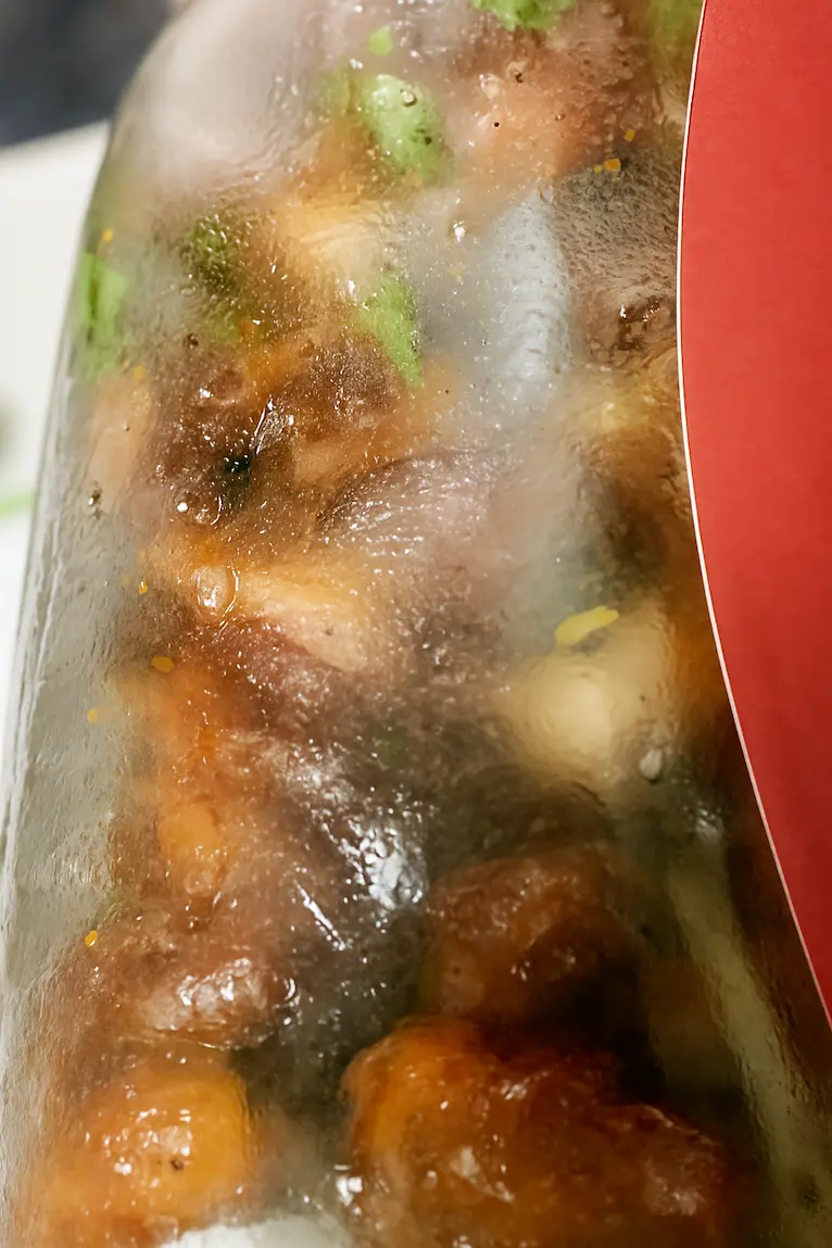 Jar filled with chicken gizzards, parsley, and onions, sealed and shaken to combine flavors
