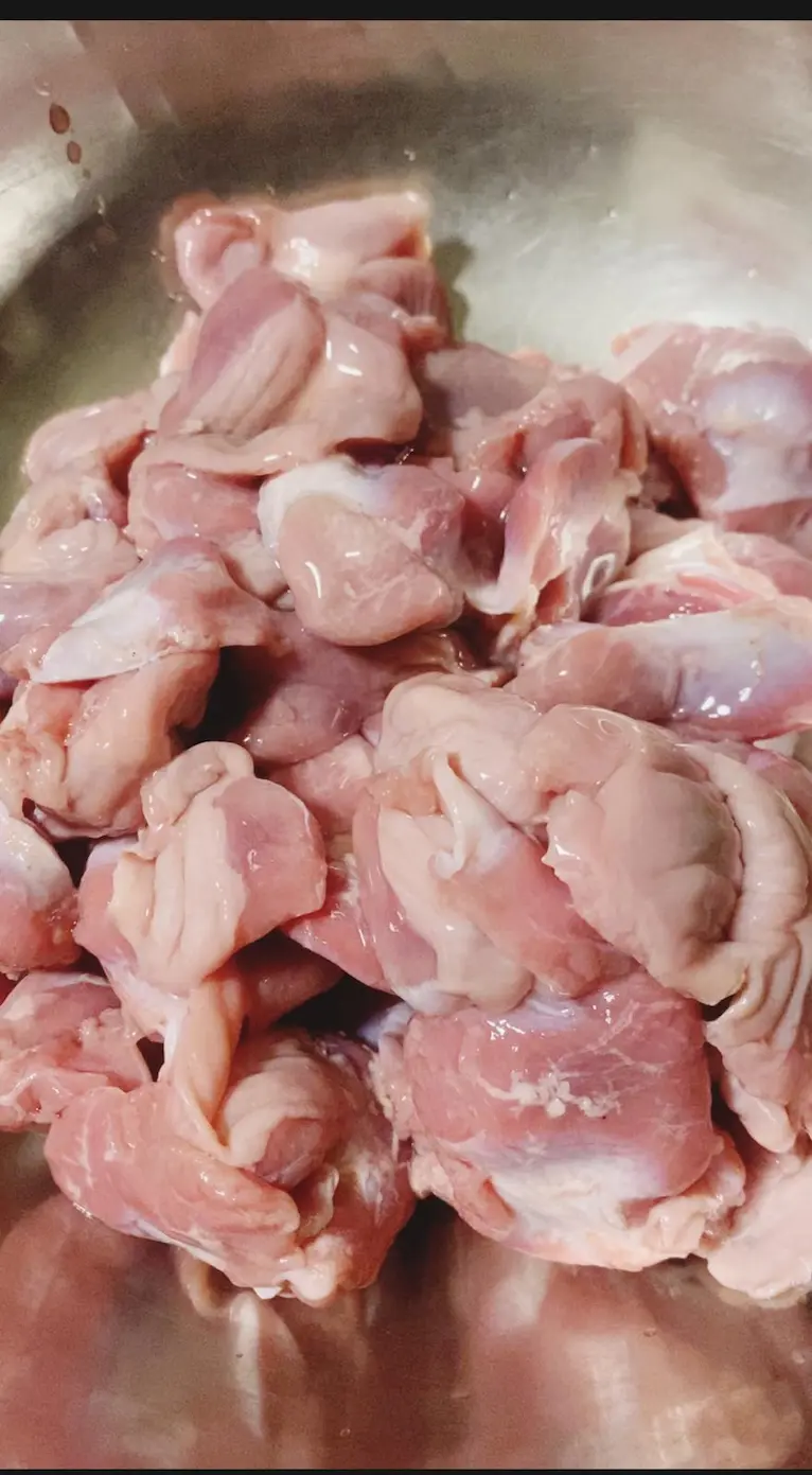 Raw, cleaned chicken gizzards in a stainless steel bowl, ready for preparation.