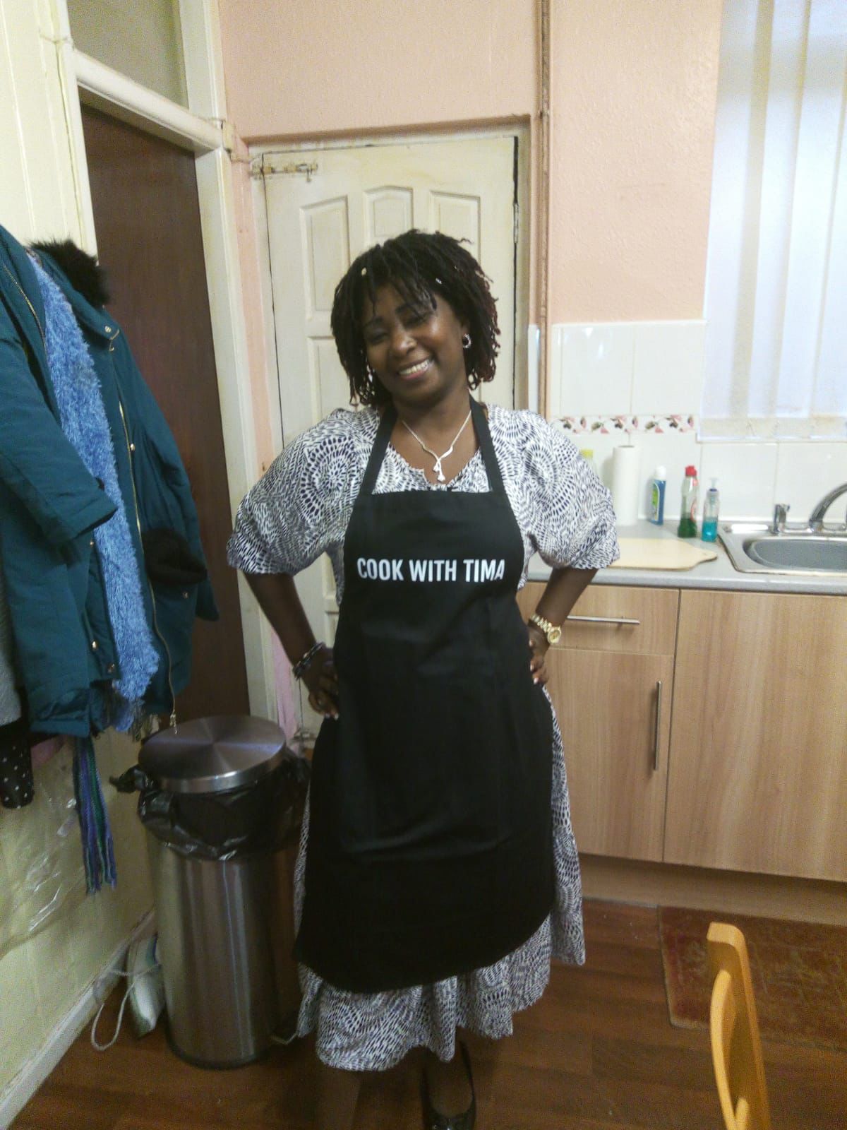 Tima smiling in her kitchen wearing a Cook With Tima apron