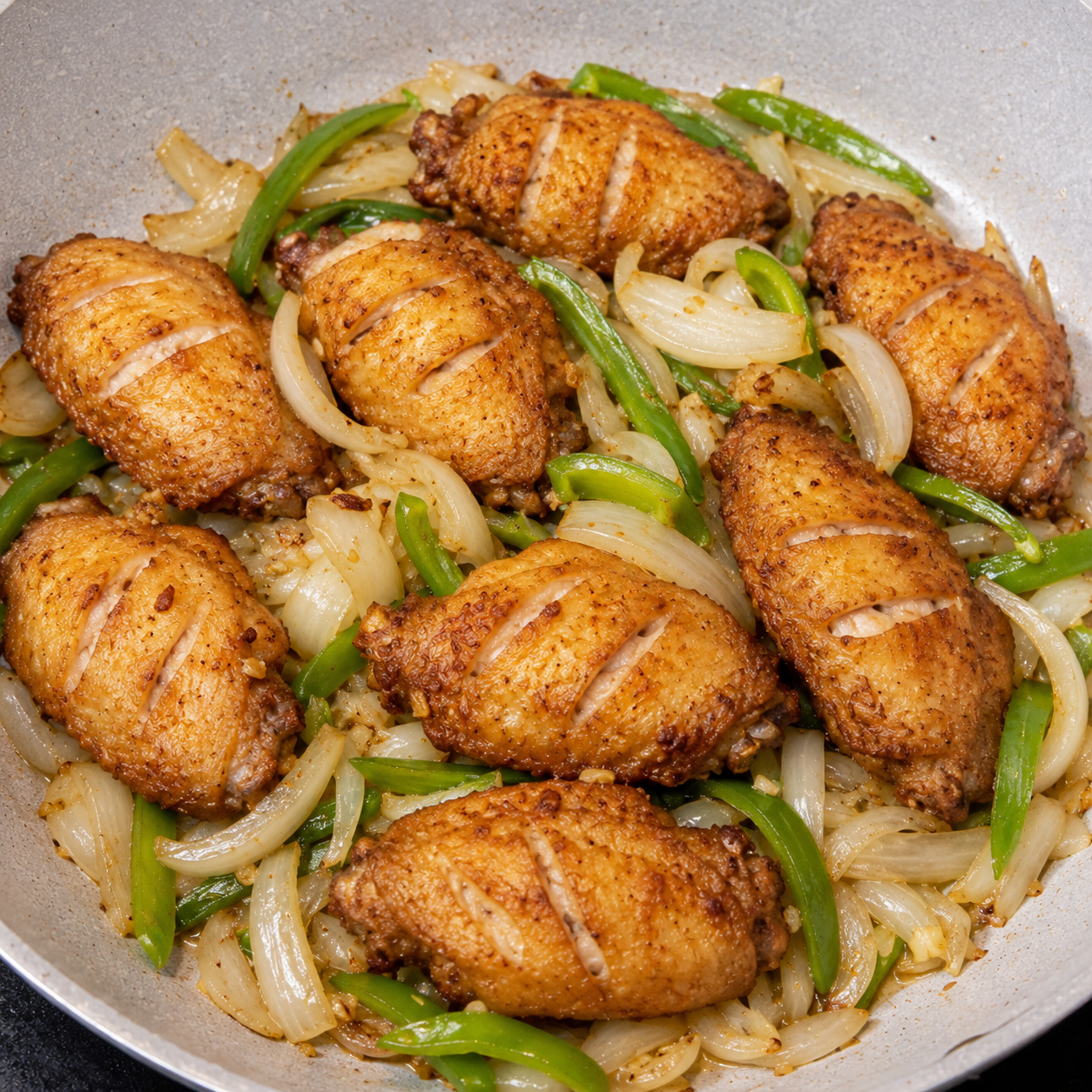 Fried chicken wings tossed with sliced onions and spring onions in a pan