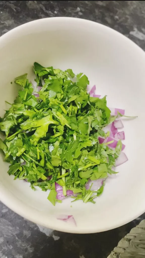 Chopped fresh parsley and red onion mixed together in a white bowl.