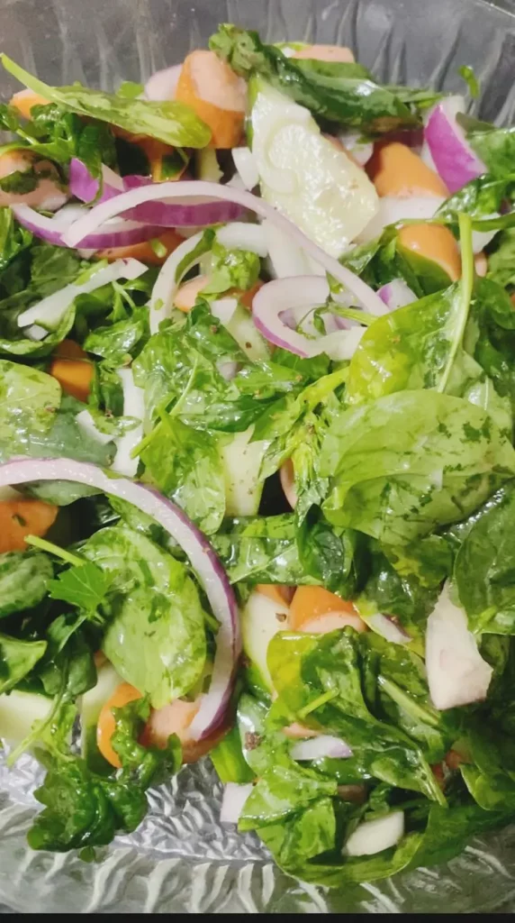 Fresh spinach and sausage salad with onions, cucumber, and parsley mixed and ready for seasoning.