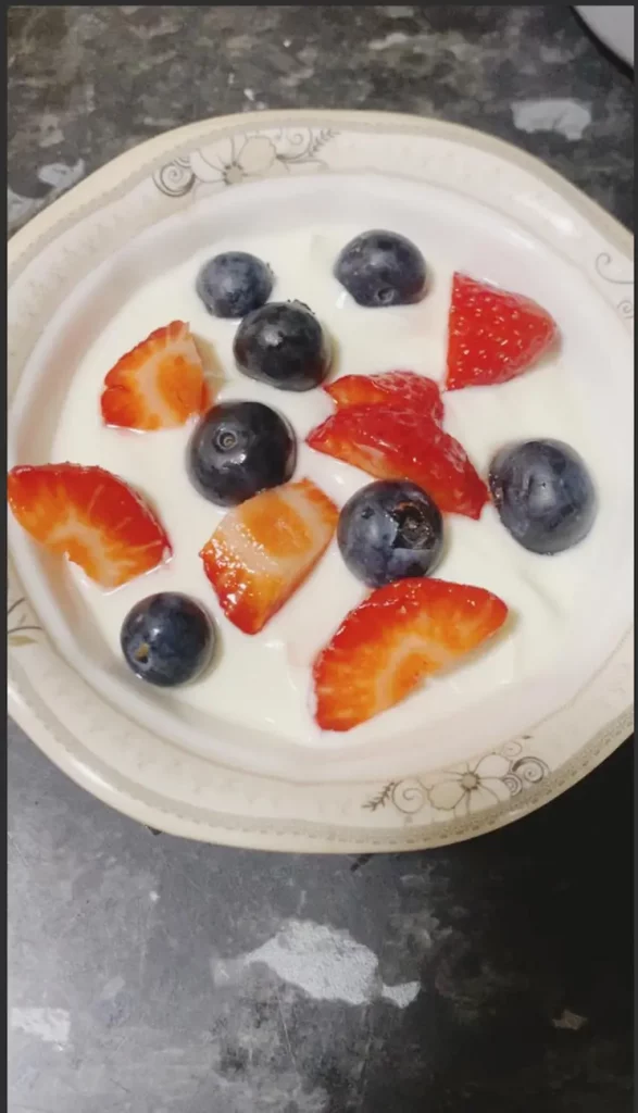 Strawberries and blueberries are arranged across yogurt.