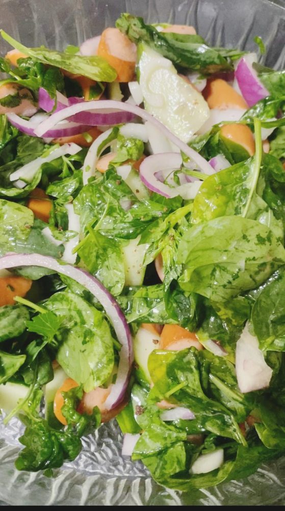 Spinach salad mixed with sausages, onions and cucumber