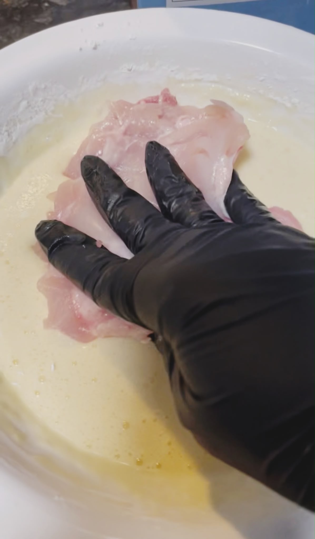 Chicken thighs coated with egg and cornflour before frying